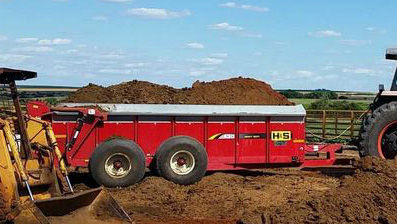 H&S manure spreader being loaded with manure to spread